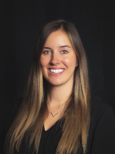 Adelia Hubbs, a white woman with long brown hair, smiles facing the camera