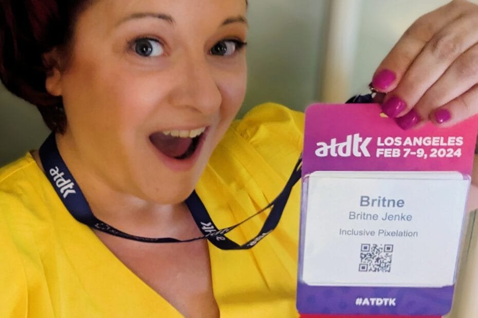 Britne holds up her speaker's badge for the ATDTK 2024 conference, she is wearing a yellow shirt and a surprised look on her face